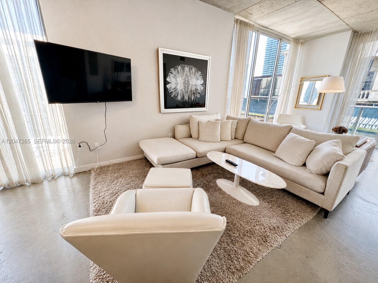 A modern living room features a sectional sofa, a coffee table, and a wall-mounted television — 151 SE 1st St # 1602, Miami FL 33131, MIAMI, FL