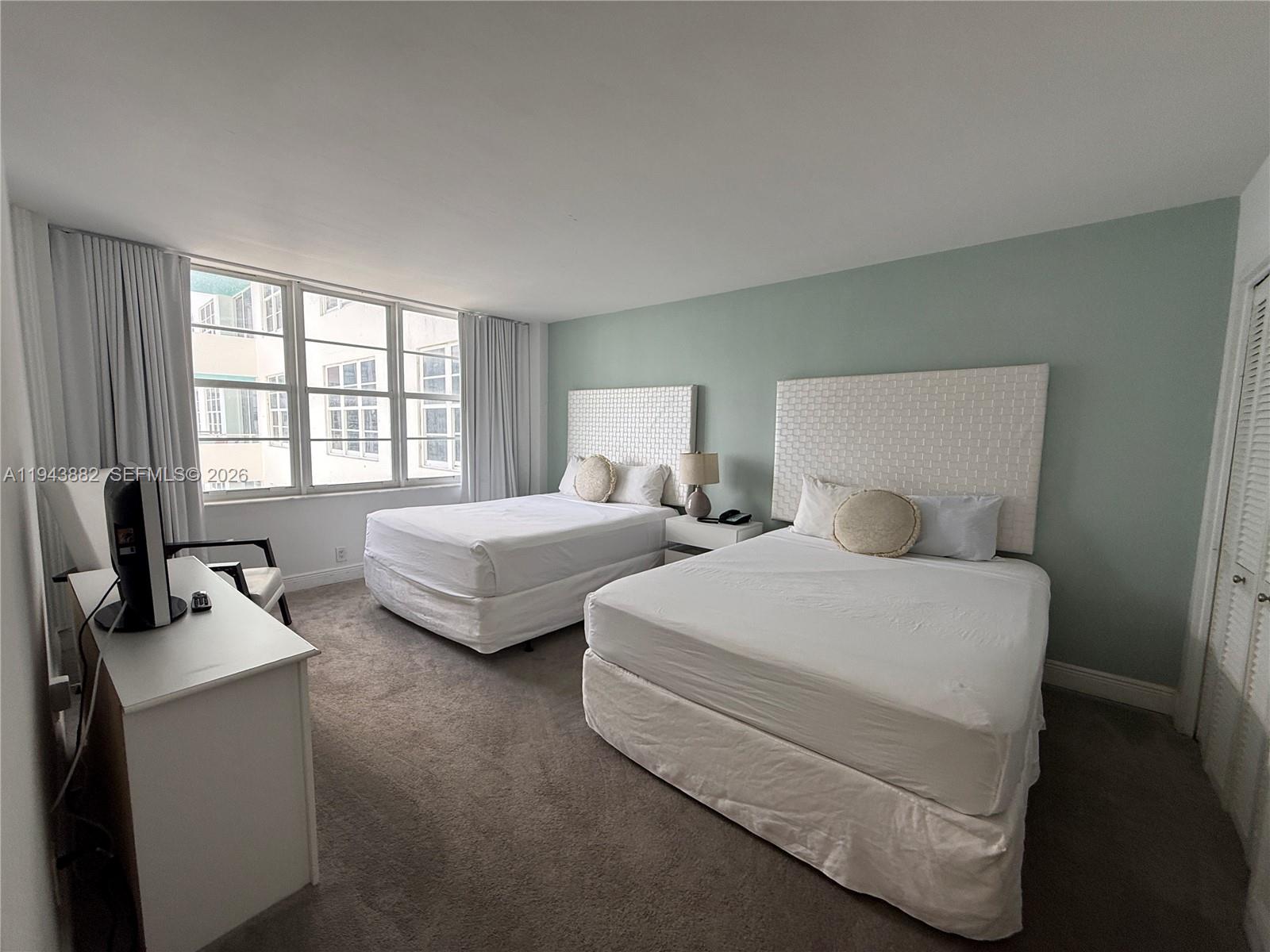 A bedroom features two beds with white headboards, a desk, and light green walls — 5101 Collins Ave # 12K, Miami Beach FL 33140, MIAMI BEACH, FL