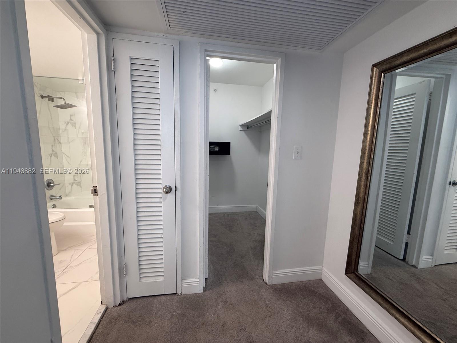 A hallway leads to a bathroom with a shower and a walk-in closet with carpet — 5101 Collins Ave # 12K, Miami Beach FL 33140, MIAMI BEACH, FL