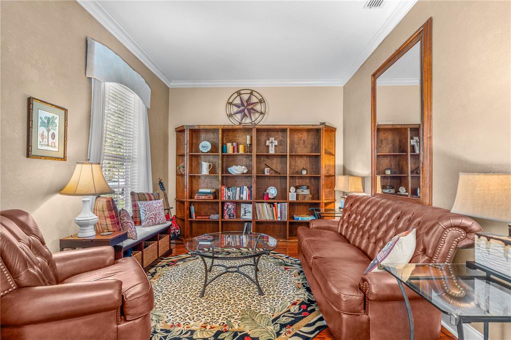 A living room features leather furniture, a large wooden bookshelf, and a patterned area rug — 3412 REXFORD CIRCLE, ORMOND BEACH, FL