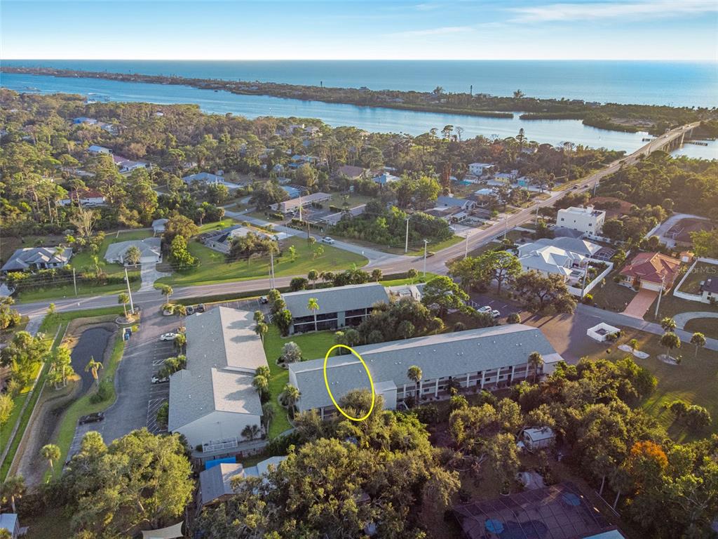 An aerial view shows a multi-story apartment complex with a yellow circle highlighting a roof section — 1730 MANASOTA BEACH ROAD UNIT 207, ENGLEWOOD, FL