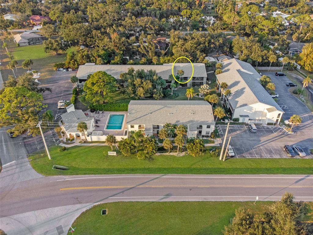 An aerial view shows a multi-story apartment complex with a swimming pool and parking lot — 1730 MANASOTA BEACH ROAD UNIT 207, ENGLEWOOD, FL