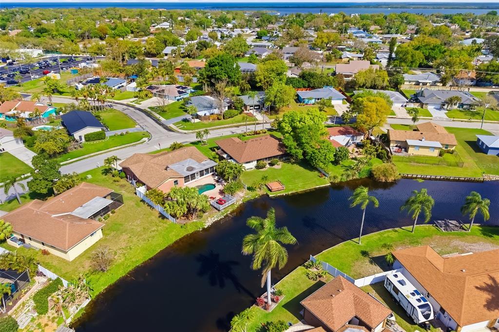 An aerial view shows suburban homes with pools and lawns bordering a narrow canal — 1207 78TH STREET NW, BRADENTON, FL