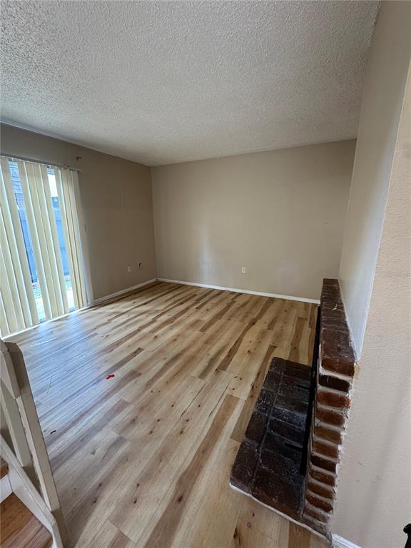 A living room features light wood-look flooring, a brick fireplace, and sliding glass patio doors — 5012 DOWNING STREET UNIT 10, ORLANDO, FL