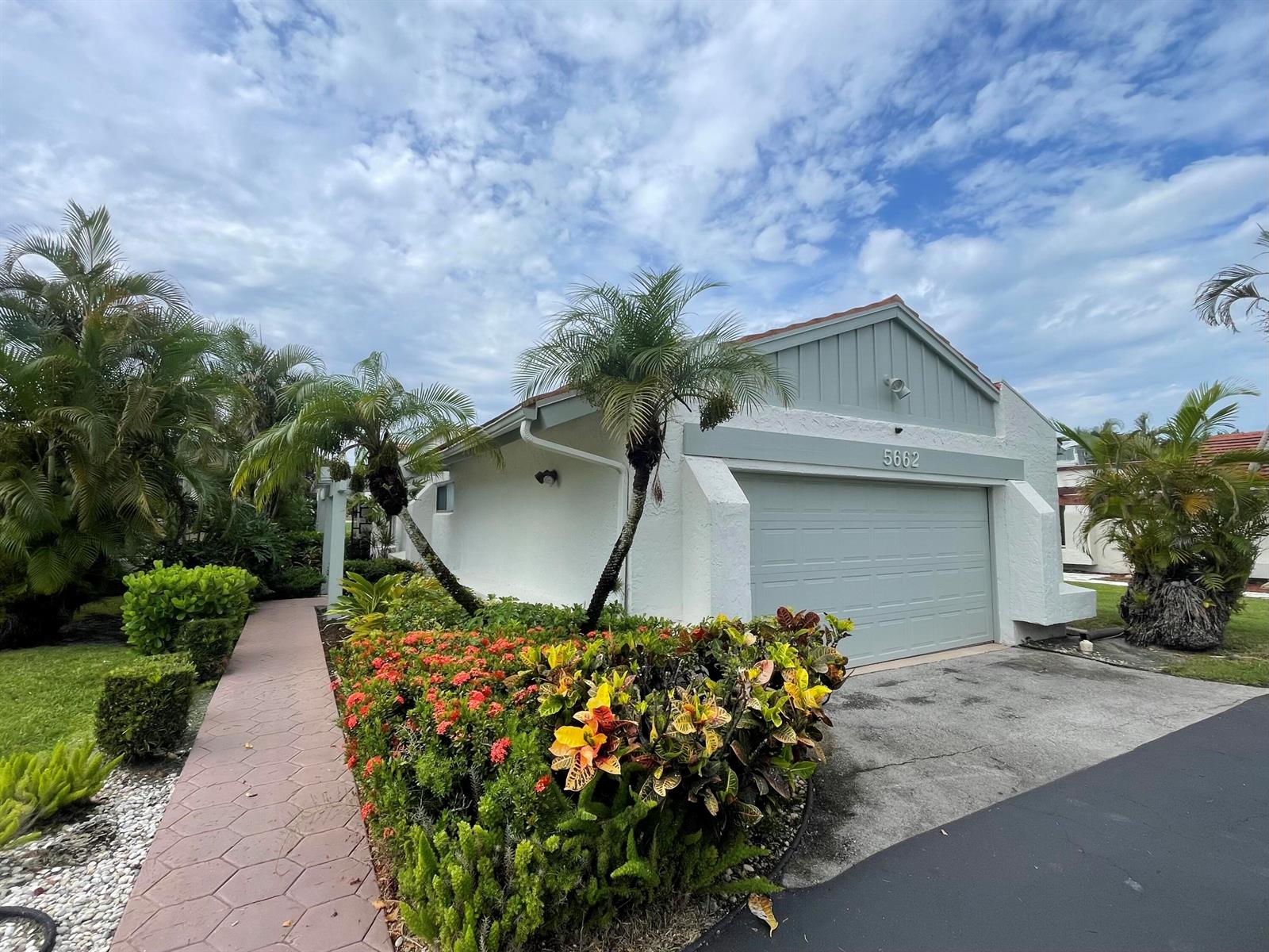 A white house with a garage and a paved walkway surrounded by tropical landscaping — 5662 Ainsley Court, Boynton Beach FL 33437, BOYNTON BEACH, FL