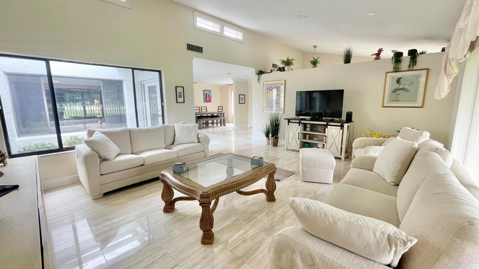 A bright living room features light-colored sofas, a glass-topped coffee table, and tile flooring — 5662 Ainsley Court, Boynton Beach FL 33437, BOYNTON BEACH, FL