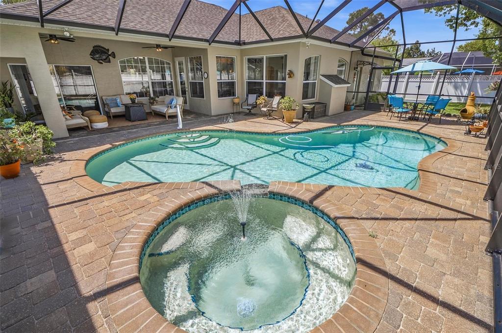 A screened-in patio features a swimming pool, a circular spa with a fountain, and furniture — 21 WOODSHIRE LANE, PALM COAST, FL