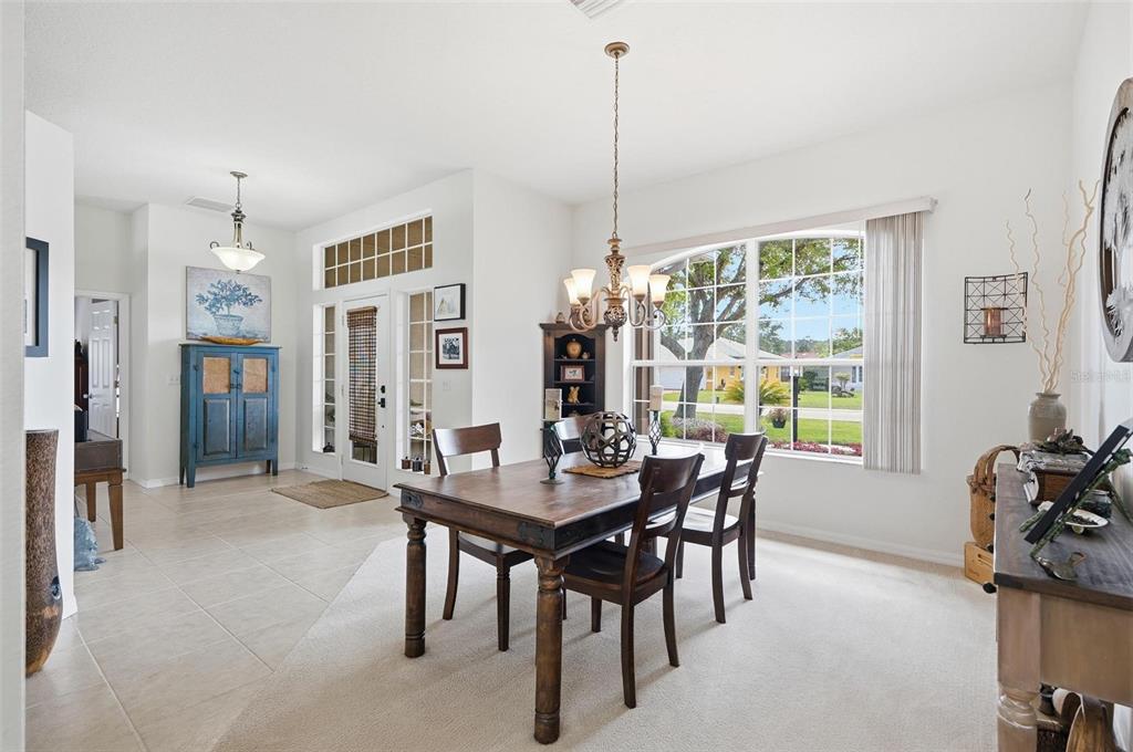 A dining room with a wooden table, chandelier, and large window overlooking a suburban street — 21 WOODSHIRE LANE, PALM COAST, FL
