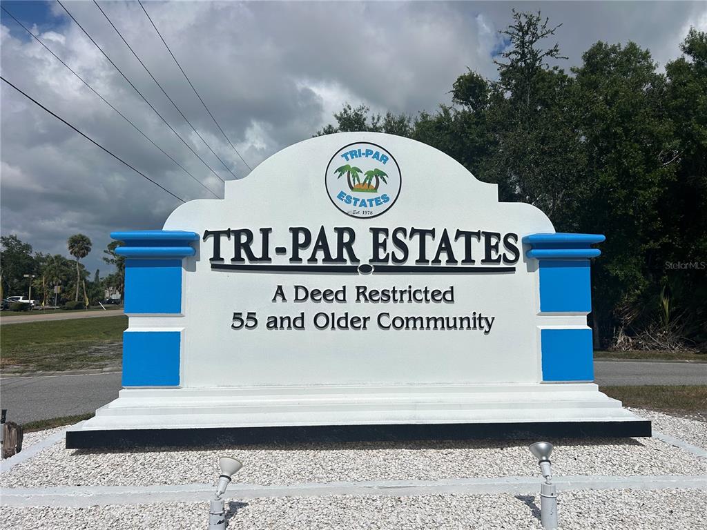 A white monument sign for Tri-Par Estates stands in a gravel area with trees behind — 1792 MIDLOTHIAN STREET, SARASOTA, FL
