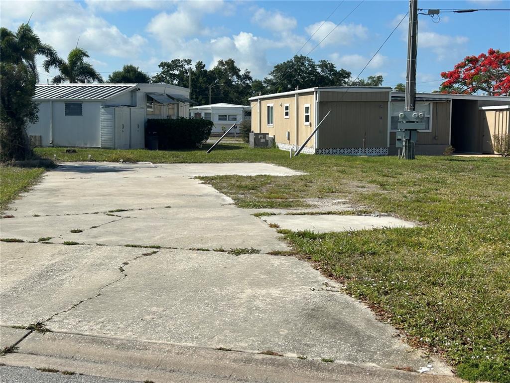 A vacant concrete lot sits in front of two mobile homes under a blue sky — 1792 MIDLOTHIAN STREET, SARASOTA, FL