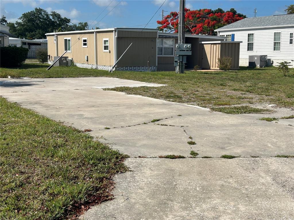 A concrete driveway leads toward a tan mobile home with a small shed nearby — 1792 MIDLOTHIAN STREET, SARASOTA, FL