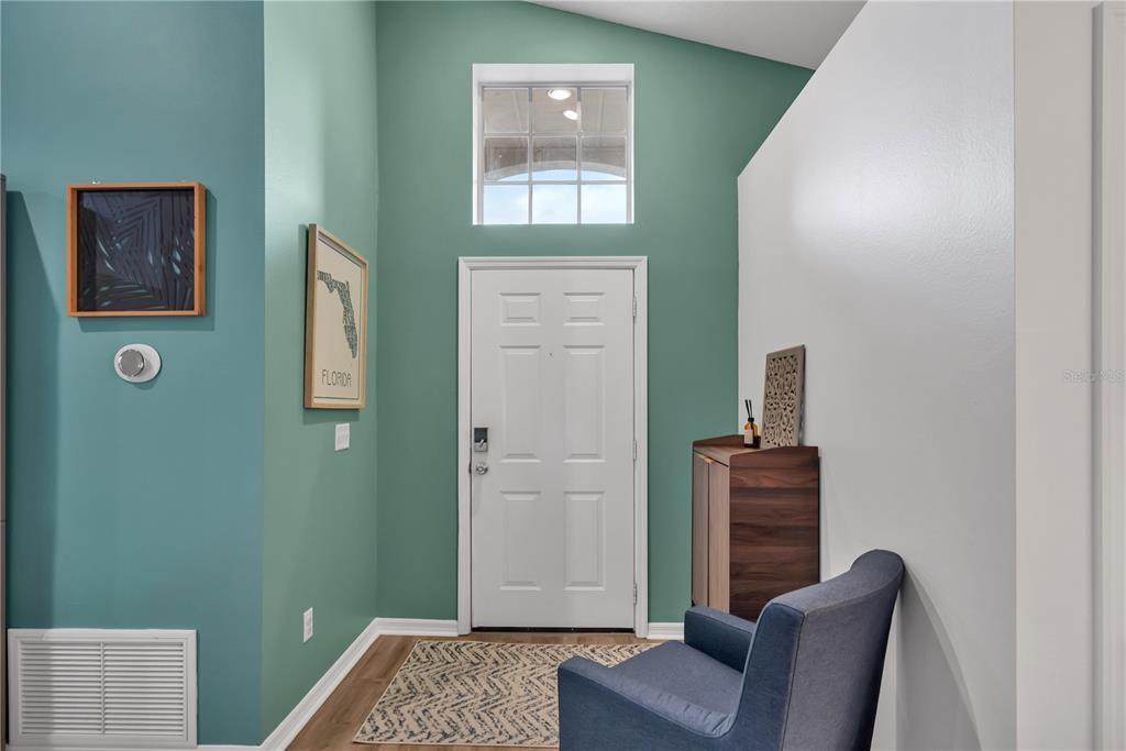 An entryway features teal walls, a white front door, a blue armchair, and wood flooring — 116 PIANO LANE, DAVENPORT, FL