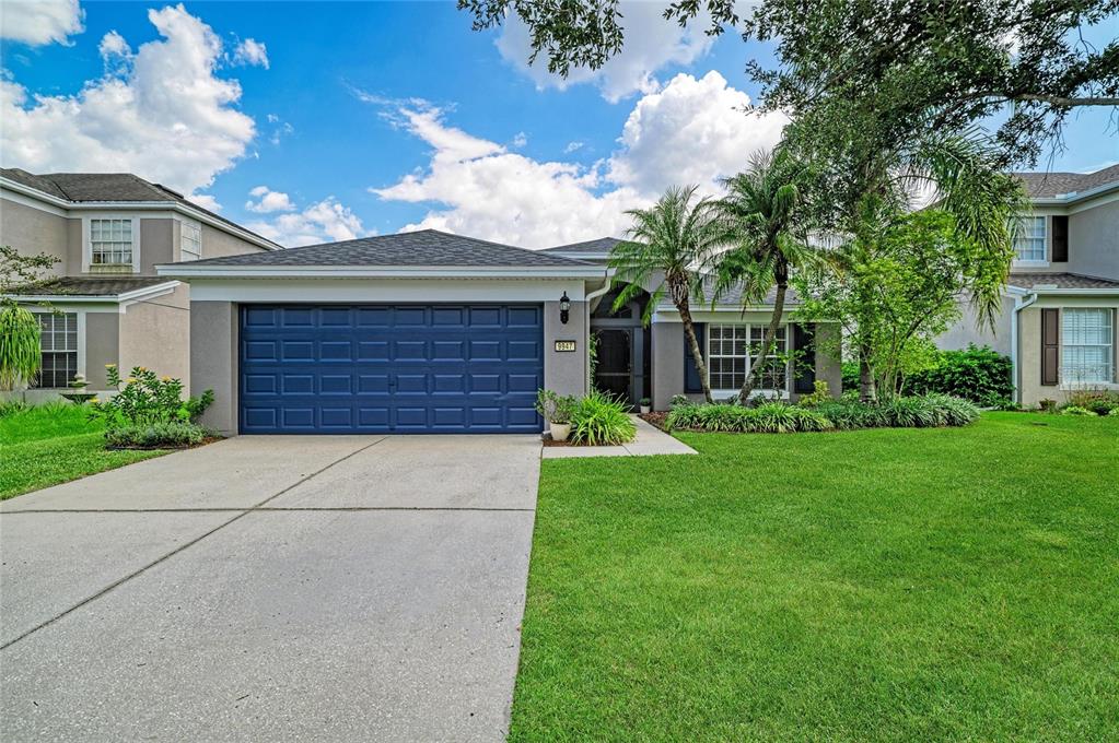 A single-story house with a blue garage door, gray exterior, and a manicured front lawn — 9947 52ND STREET E, PARRISH, FL