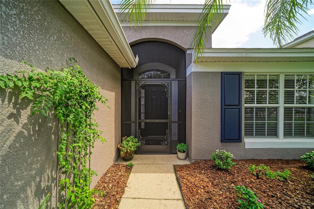 The exterior of a home features a dark front door with a screen enclosure — 9947 52ND STREET E, PARRISH, FL