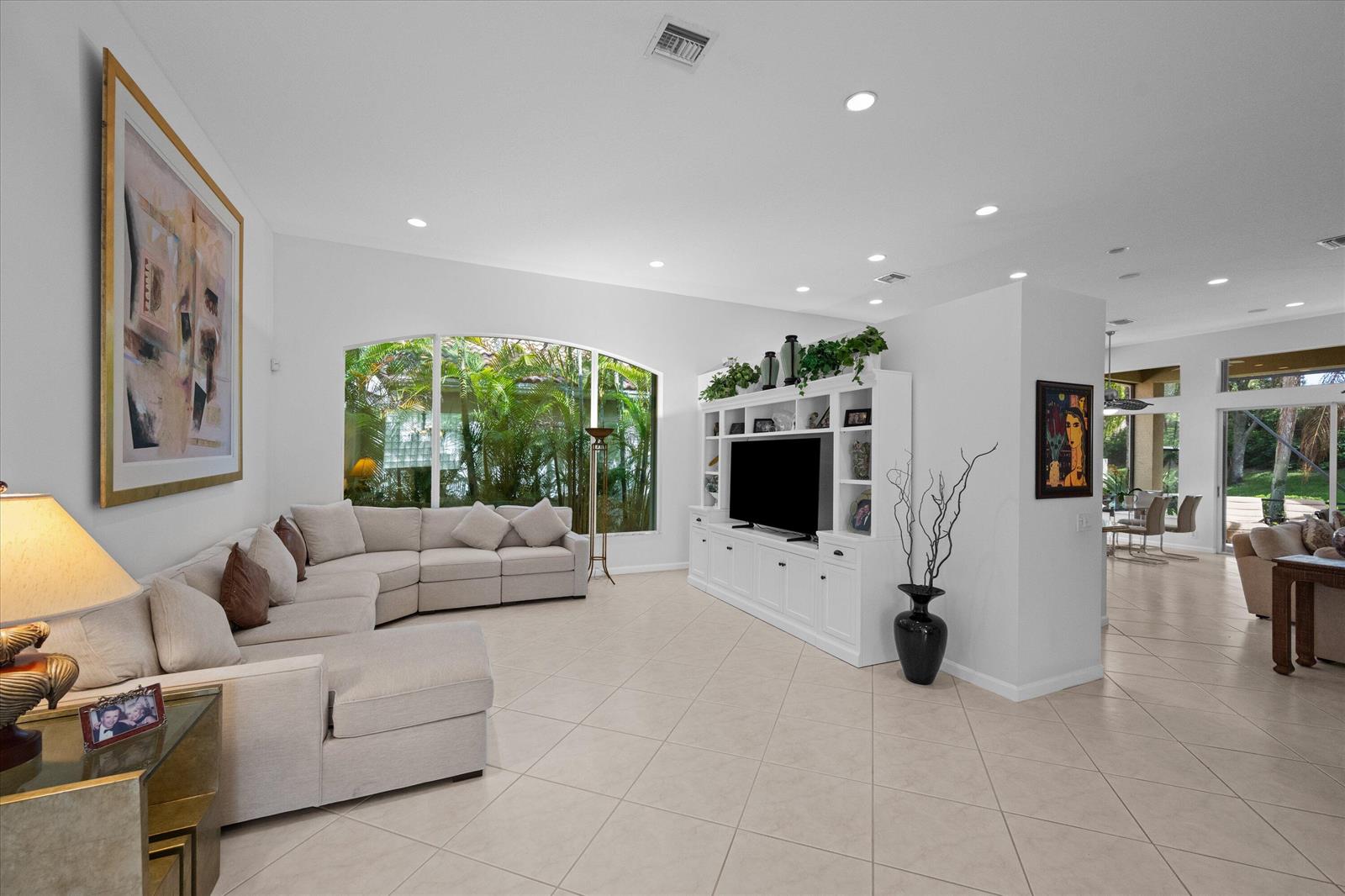 A living room features a large sectional sofa, a white media console, and tile flooring — 10689 Northgreen Drive, Lake Worth FL 33449, LAKE WORTH, FL