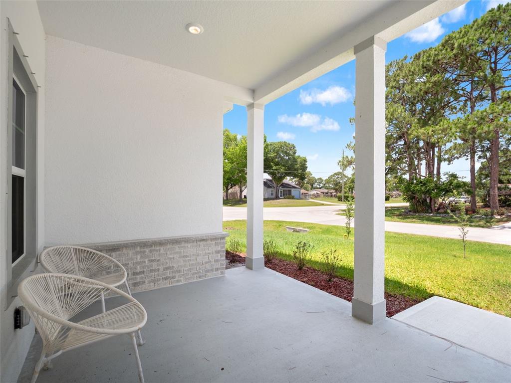 A covered front porch features white columns, a concrete floor, and two white chairs — 1406 VALERIUS STREET SE, PALM BAY, FL
