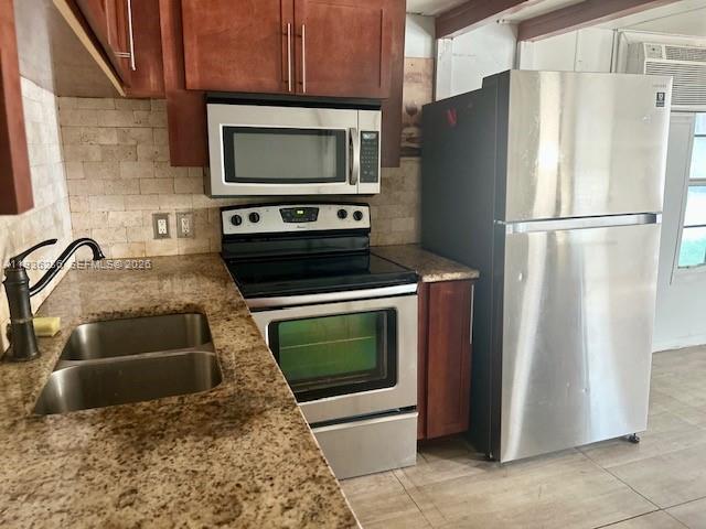 A kitchen features stainless steel appliances, wood cabinets, and granite countertops with a double sink — 8732 SW 16th St, Davie FL 33324, DAVIE, FL