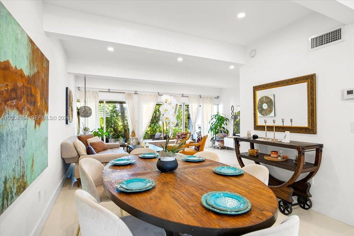A dining area with a wooden oval table opens into a bright living room — 19220 NE 25th Ave # 274B, Miami FL 33180, MIAMI, FL