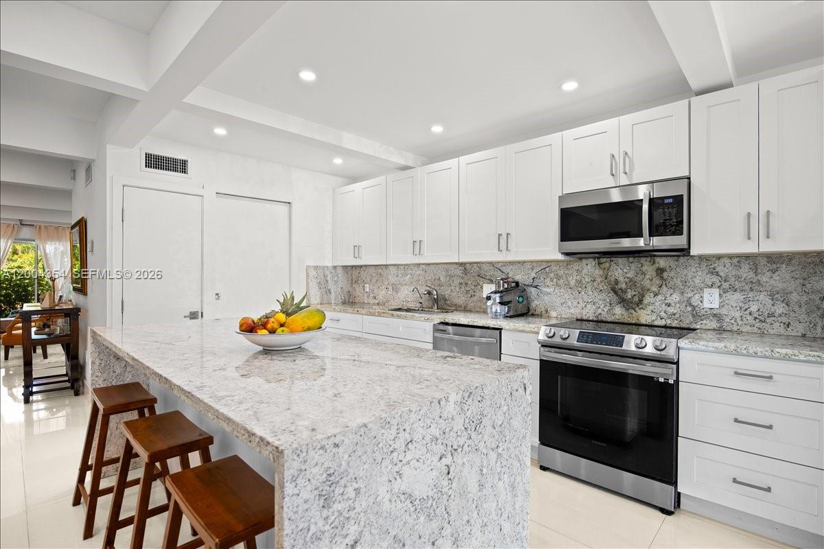 A kitchen features white cabinets, granite countertops, a large island, and stainless steel appliances — 19220 NE 25th Ave # 274B, Miami FL 33180, MIAMI, FL