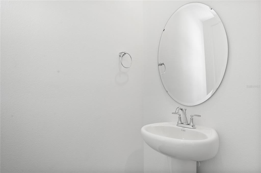 A white pedestal sink with a chrome faucet sits below an oval wall mirror — 716 LAKE DELL AVENUE, DUNDEE, FL