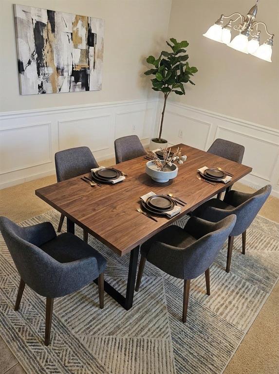 A dining room features a wooden table with six gray chairs on a patterned rug — 9831 DEL WEBB PARKWAY UNIT 4208, JACKSONVILLE, FL