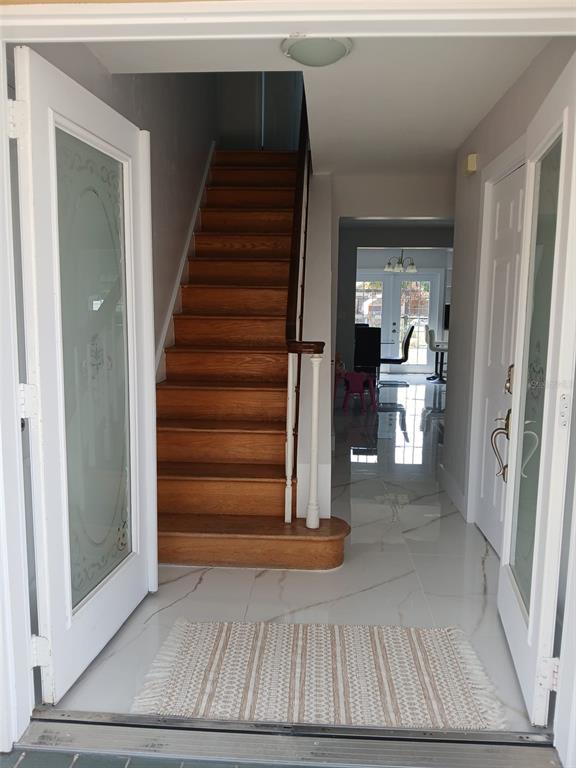 An entryway features a wooden staircase, white tiled floors, and double doors with glass inserts — 2211 NEW JERSEY ROAD, LAKELAND, FL