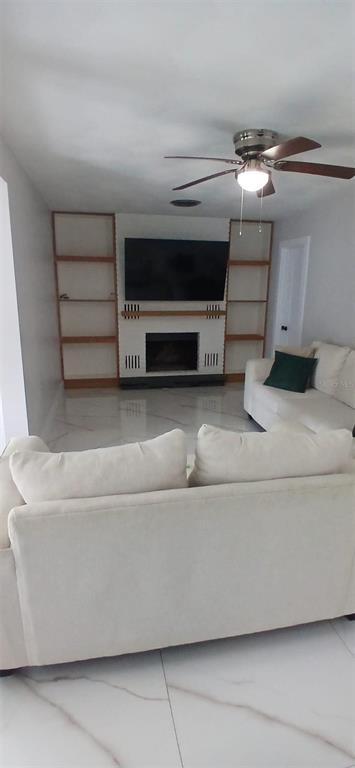 A living room features white sofas, a fireplace with built-in shelving, and light-colored tile flooring — 2211 NEW JERSEY ROAD, LAKELAND, FL