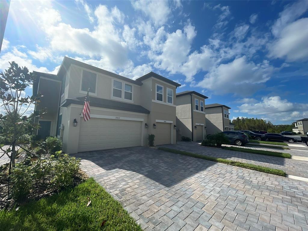 A two-story townhouse with a paved driveway, a two-car garage, and an American flag — 29850 SOUTHWELL LANE, WESLEY CHAPEL, FL