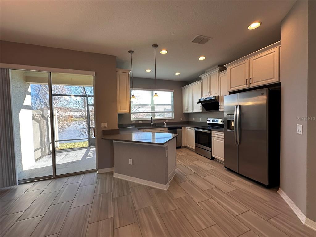 A kitchen with white cabinets, stainless steel appliances, a breakfast bar, and tile flooring — 29850 SOUTHWELL LANE, WESLEY CHAPEL, FL