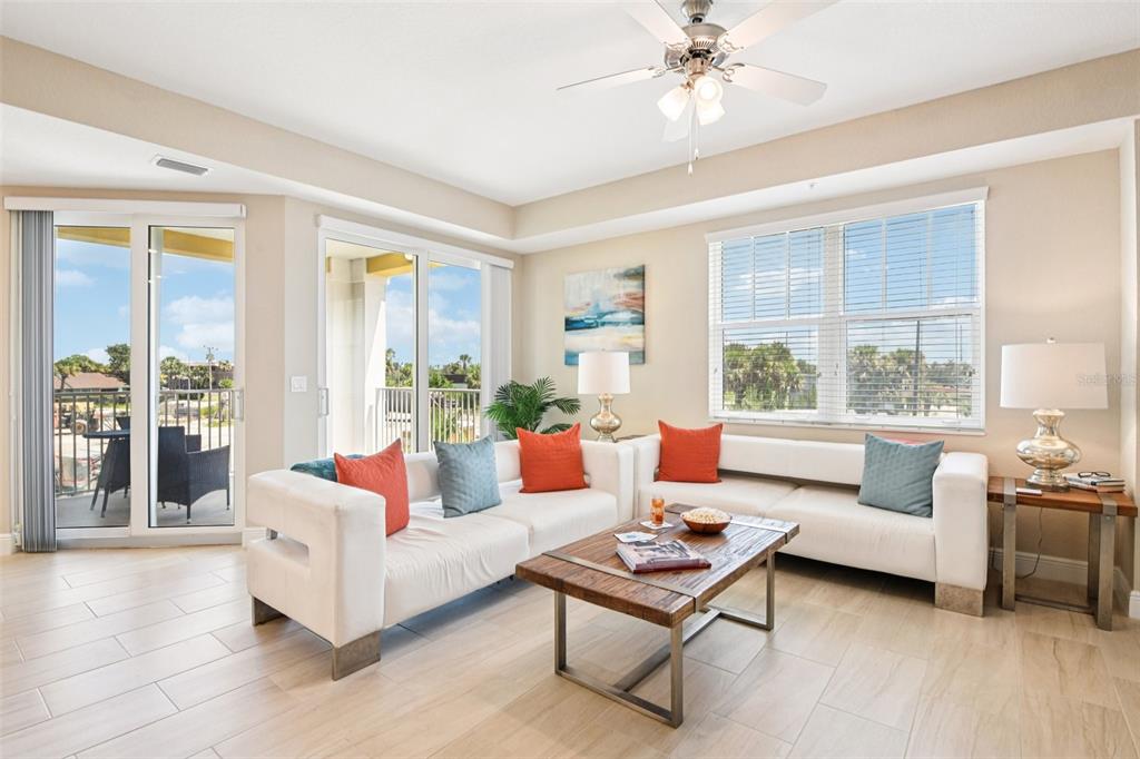 A bright living room features a white sectional sofa, a wooden coffee table, and sliding doors — 7 RIVERWALK DRIVE UNIT 307, NEW SMYRNA BEACH, FL