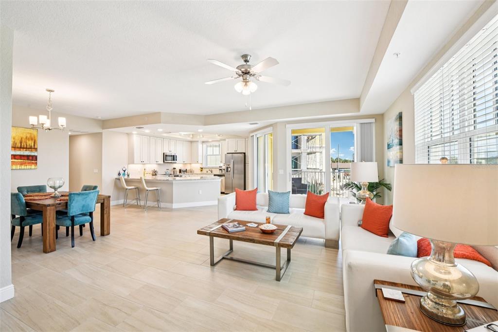 An open-concept living and dining area features light tile flooring, white sofas, and a kitchen — 7 RIVERWALK DRIVE UNIT 307, NEW SMYRNA BEACH, FL