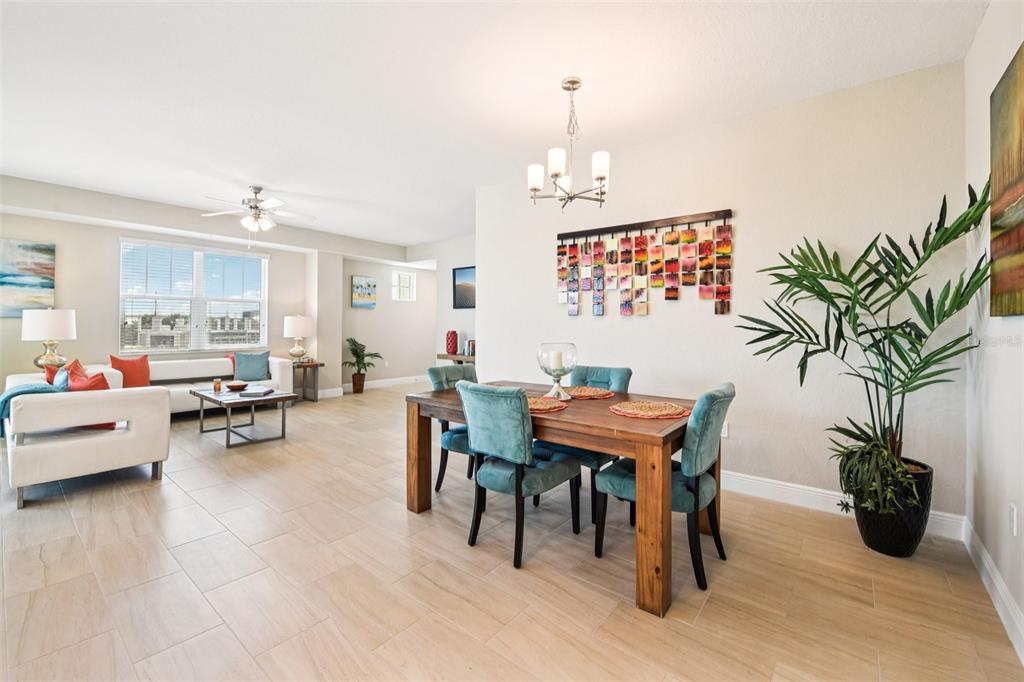 A dining area with a wooden table and teal chairs sits beside a living room — 7 RIVERWALK DRIVE UNIT 307, NEW SMYRNA BEACH, FL