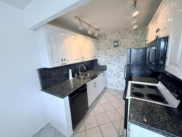 A kitchen features white cabinets, dark granite countertops, black appliances, and patterned wallpaper — 4065 Harwood E, Deerfield Beach FL 33442, DEERFIELD BEACH, FL