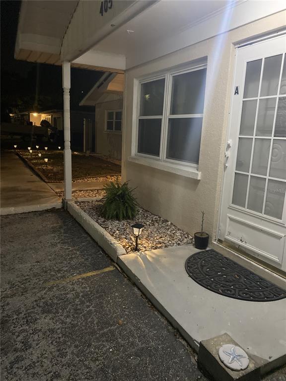 The exterior of a residential unit features a covered entryway, a small garden bed, and a door — 405 S ORION AVENUE, CLEARWATER, FL