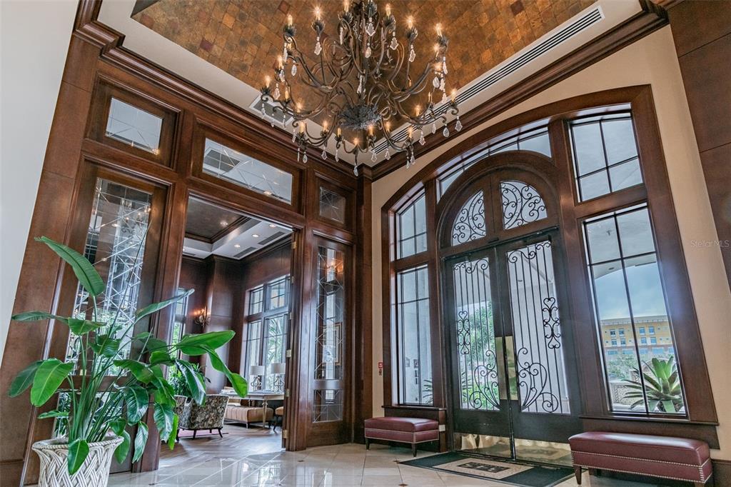 A grand foyer features a large chandelier, dark wood trim, and arched glass double doors — 345 BAYSHORE BOULEVARD UNIT 1206, TAMPA, FL