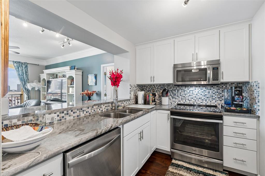 A kitchen with white cabinets, stainless steel appliances, granite countertops, and a mosaic tile backsplash — 345 BAYSHORE BOULEVARD UNIT 1206, TAMPA, FL