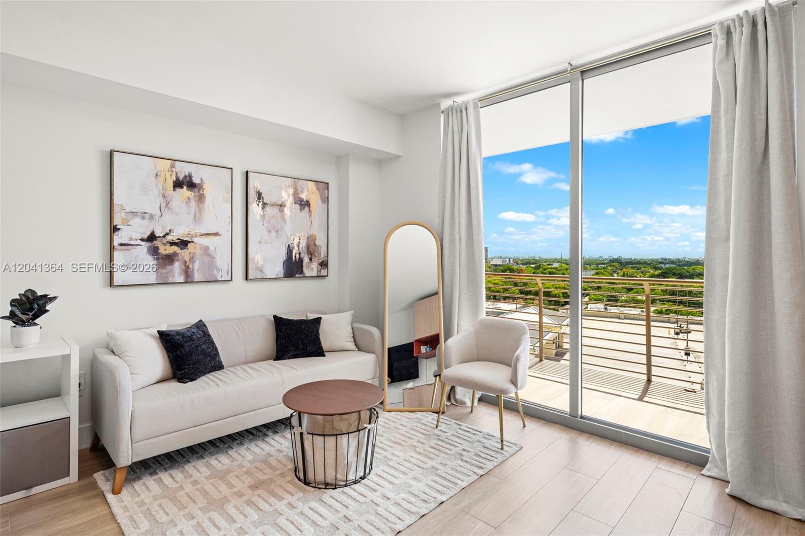 A living room features a light-colored sofa, a round coffee table, and a balcony view — 90 NE 32nd St # 925, Miami FL 33137, MIAMI, FL