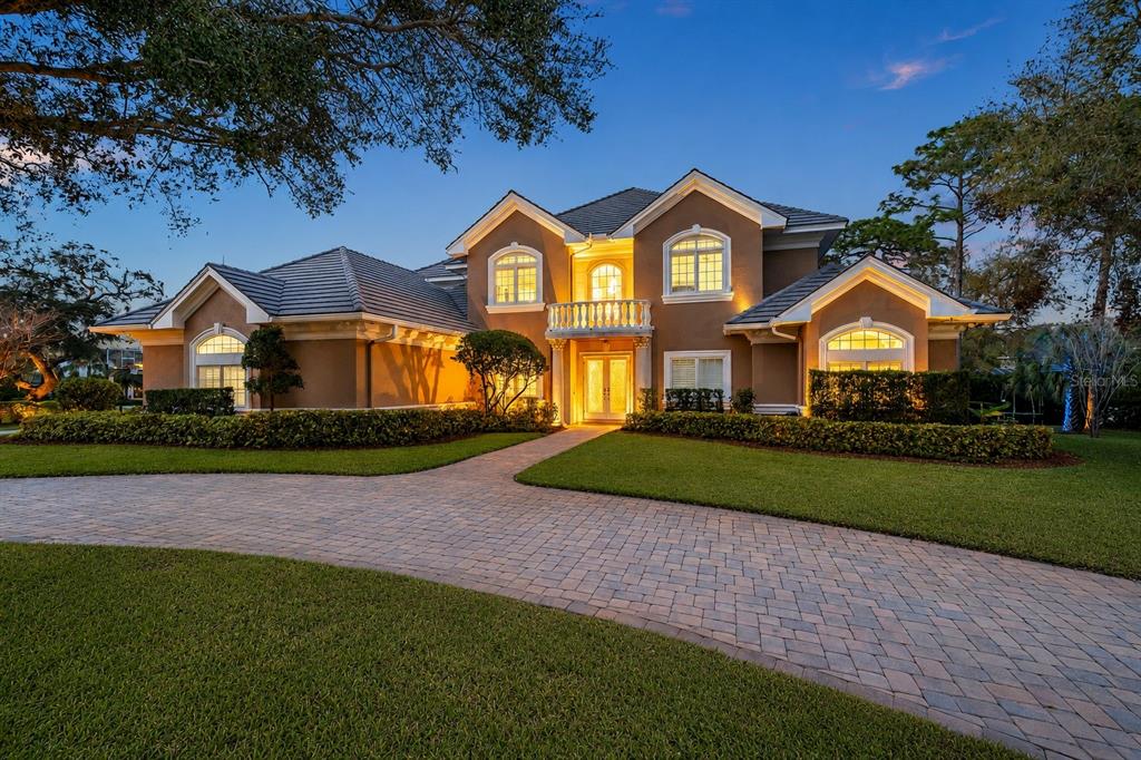 A two-story house with a paved driveway, tan stucco exterior, and a tiled roof — 2280 MACKENZIE COURT, CLEARWATER, FL