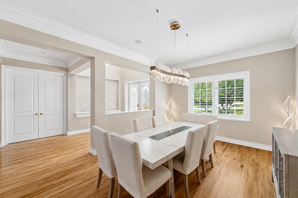 A dining room features a long table with six chairs, a crystal chandelier, and hardwood floors — 2280 MACKENZIE COURT, CLEARWATER, FL