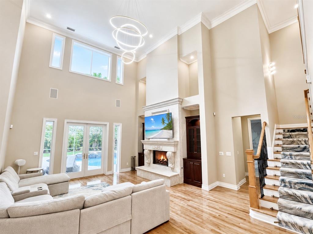 A high-ceilinged living room features a stone fireplace, a sectional sofa, and a staircase — 2280 MACKENZIE COURT, CLEARWATER, FL