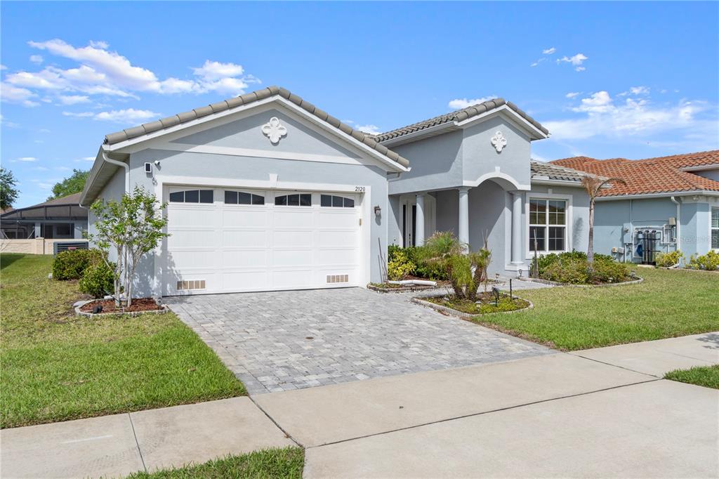 A single-story house with a light blue exterior, a two-car garage, and a paved driveway — 2320 SYMPHONY CIRCLE, ST CLOUD, FL