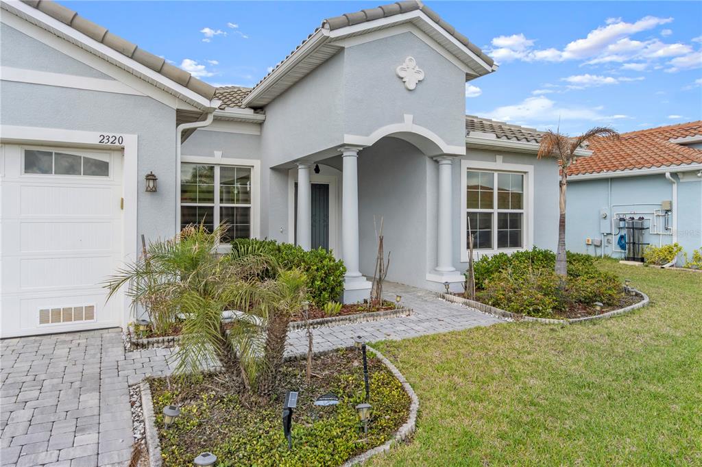 A single-story house with a gray stucco exterior, a paved walkway, and a palm tree — 2320 SYMPHONY CIRCLE, ST CLOUD, FL