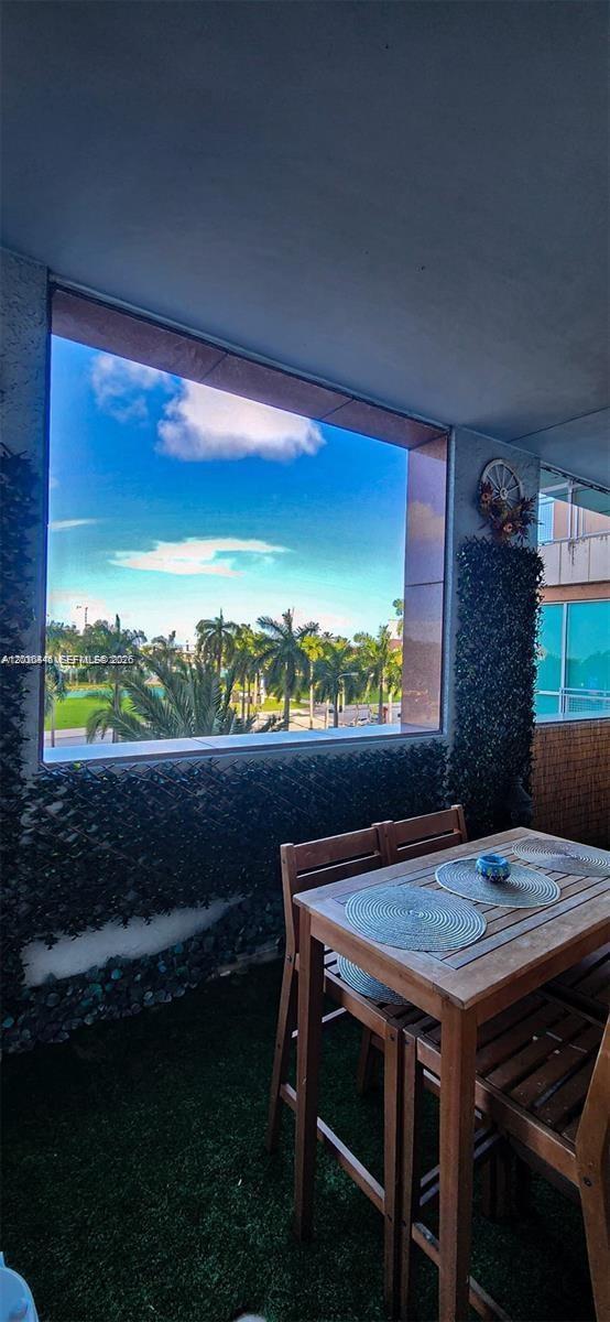A balcony features artificial grass, a wooden dining set, and a view of palm trees — 244 Biscayne Blvd # 301, Miami FL 33132, MIAMI, FL