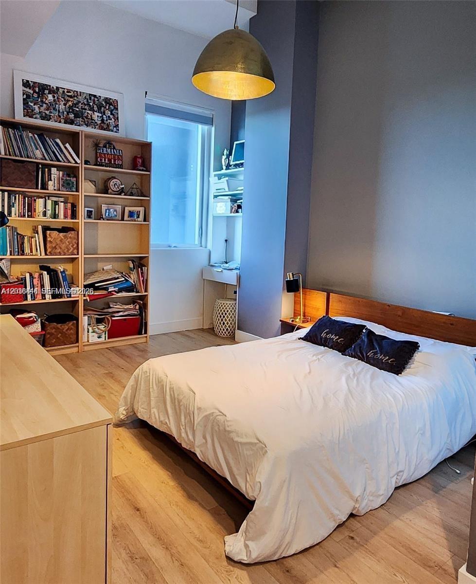 A bedroom features a bed with a wooden headboard, a tall bookshelf, and a desk — 244 Biscayne Blvd # 301, Miami FL 33132, MIAMI, FL