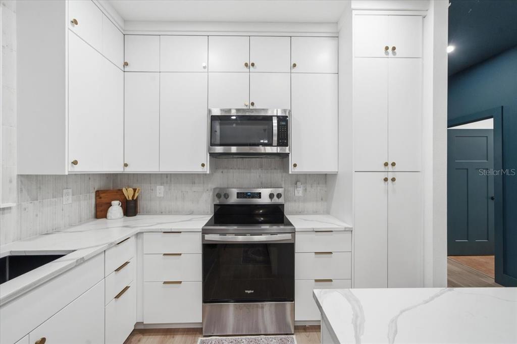 A modern kitchen features white cabinets, stainless steel appliances, and white marble-look countertops — 2601 E 24TH AVENUE, TAMPA, FL