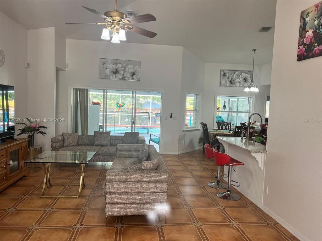 A living room and kitchen area feature tile flooring, a ceiling fan, and sliding glass doors — 713 5TH AVENUE, LEHIGH ACRES, FL