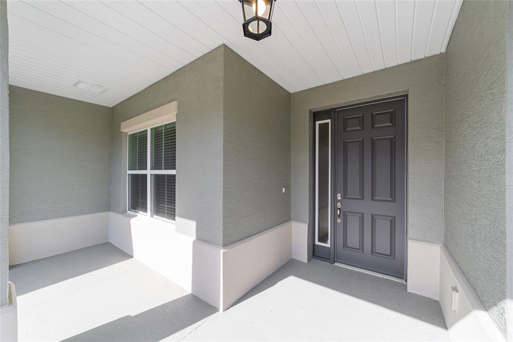 A covered front porch features a gray door with a sidelight and a single window — 10372 SW 105TH COURT, OCALA, FL