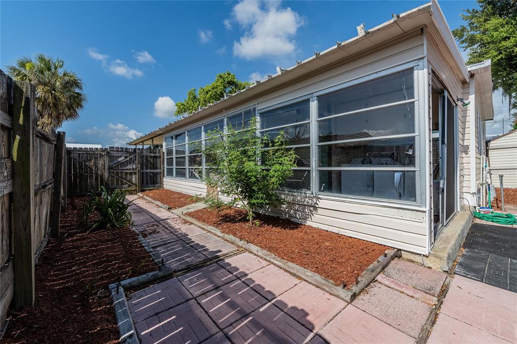 A side view of a mobile home with a screened-in porch, brick walkway, and fence — 36749 JODI AVENUE, ZEPHYRHILLS, FL