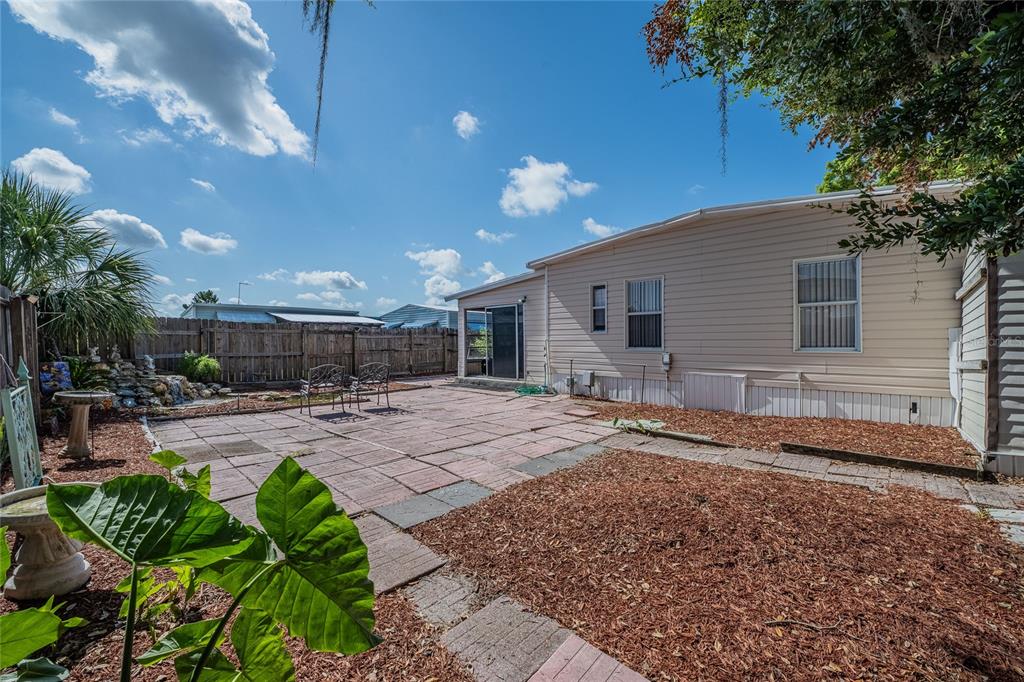 A backyard features a paved patio, a mulch area, and a light-colored mobile home exterior — 36749 JODI AVENUE, ZEPHYRHILLS, FL
