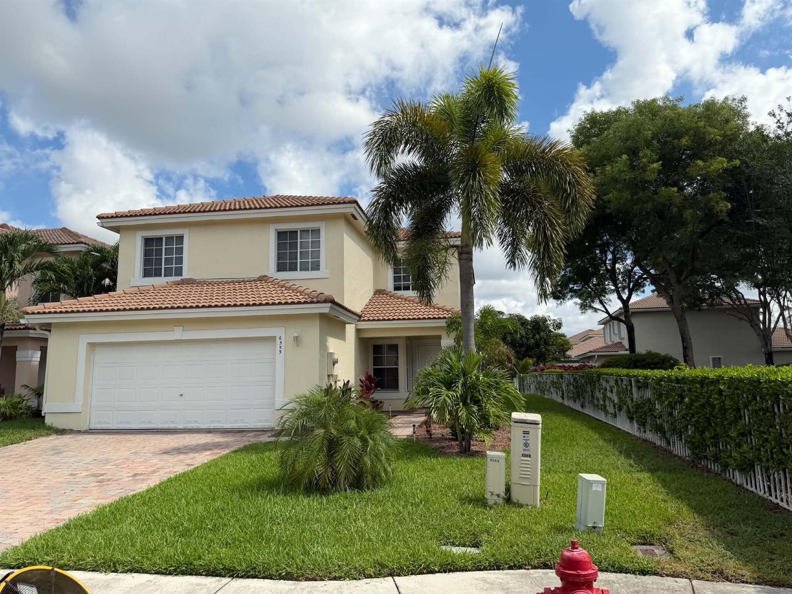 A two-story, light-yellow stucco house with a tile roof, a garage, and a palm tree — 6355 Adriatic Way, West Palm Beach FL 33413, WEST PALM BEACH, FL